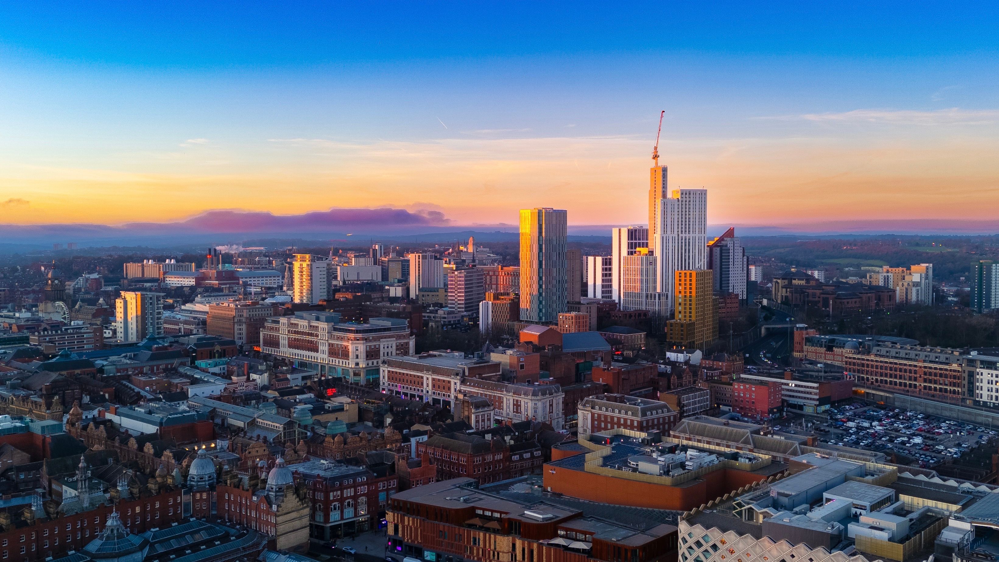 Stunning aerial view of Leeds city skyline in England during sunset with vibrant colors.